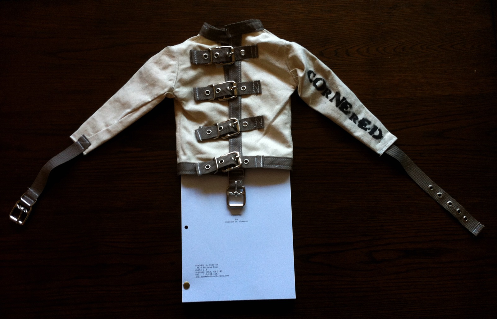 The CORNERED screenplay bound in a miniature straitjacket